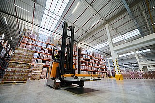 Reach truck STILL FM-X z platformą transportową na widłach.